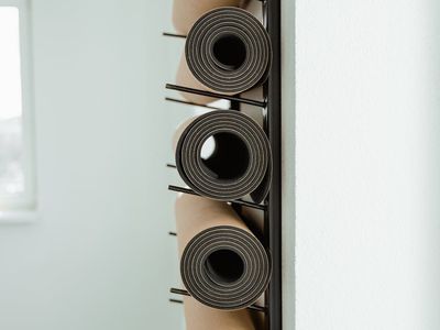 A rolled yoga mat leaning against a magenta wall.