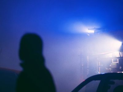 Person doing a tree pose silhouette against neon light.